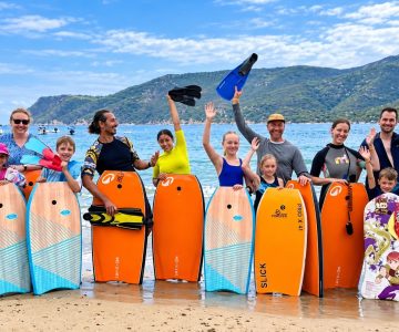 Corso di Bodyboard Gruppo sorridente con bodyboard in spiaggia